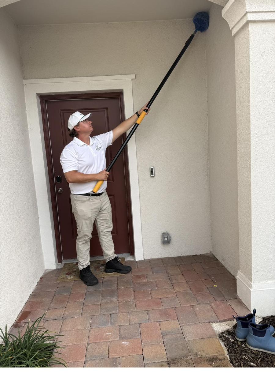 RJ clearing spider webs from a front entryway